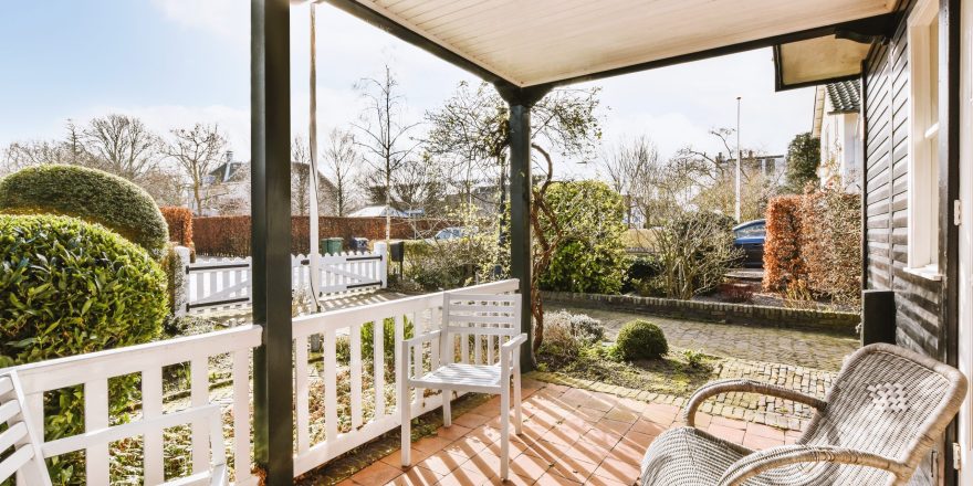 Neat paved patio with sitting area and small garden near wooden fence