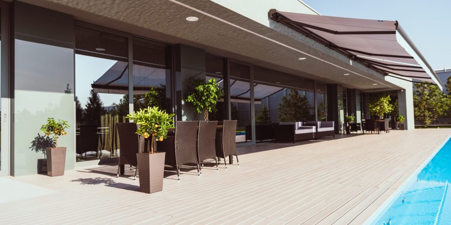 swimming pool and porch of modern country house with little trees, chairs and tables