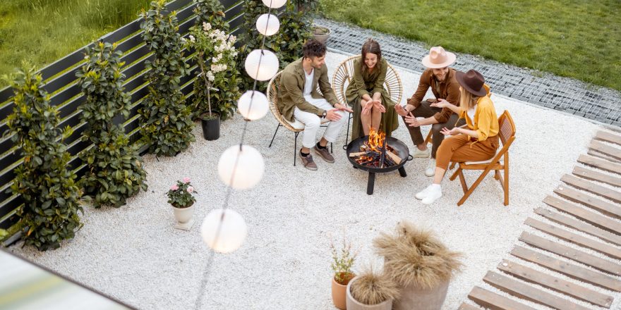 A group of young friends having great summertime, sitting by a fireplace at the backyard of the country house in nature. Top view